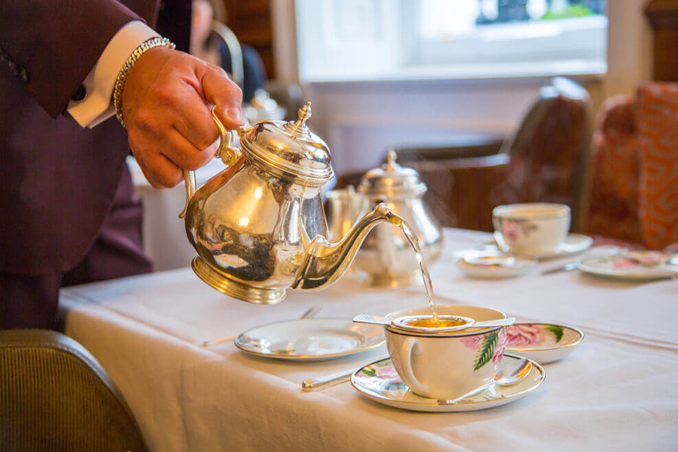 Tea being poured in elegant surroundings. An example of Afternoon Tea etiquette.